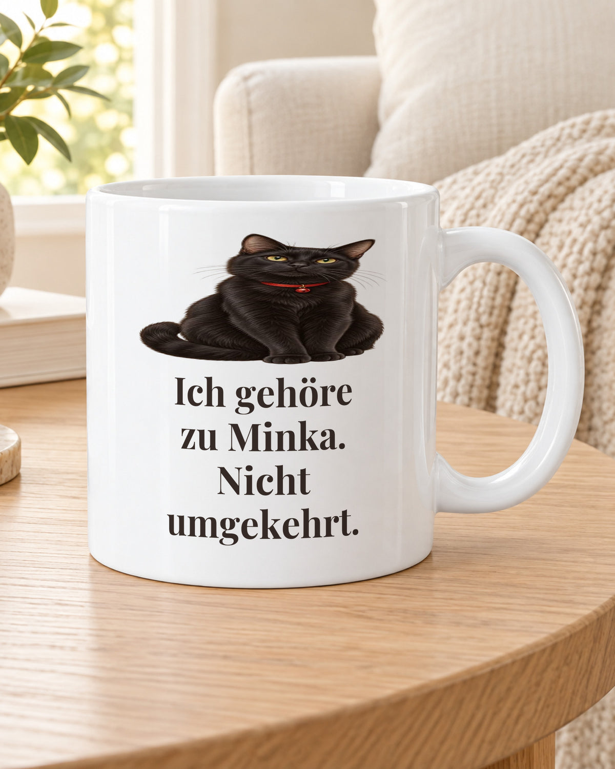 Katzentasse „Ich gehöre zu Minka. Nicht umgekehrt.“ auf dem Beistelltisch am Sofa