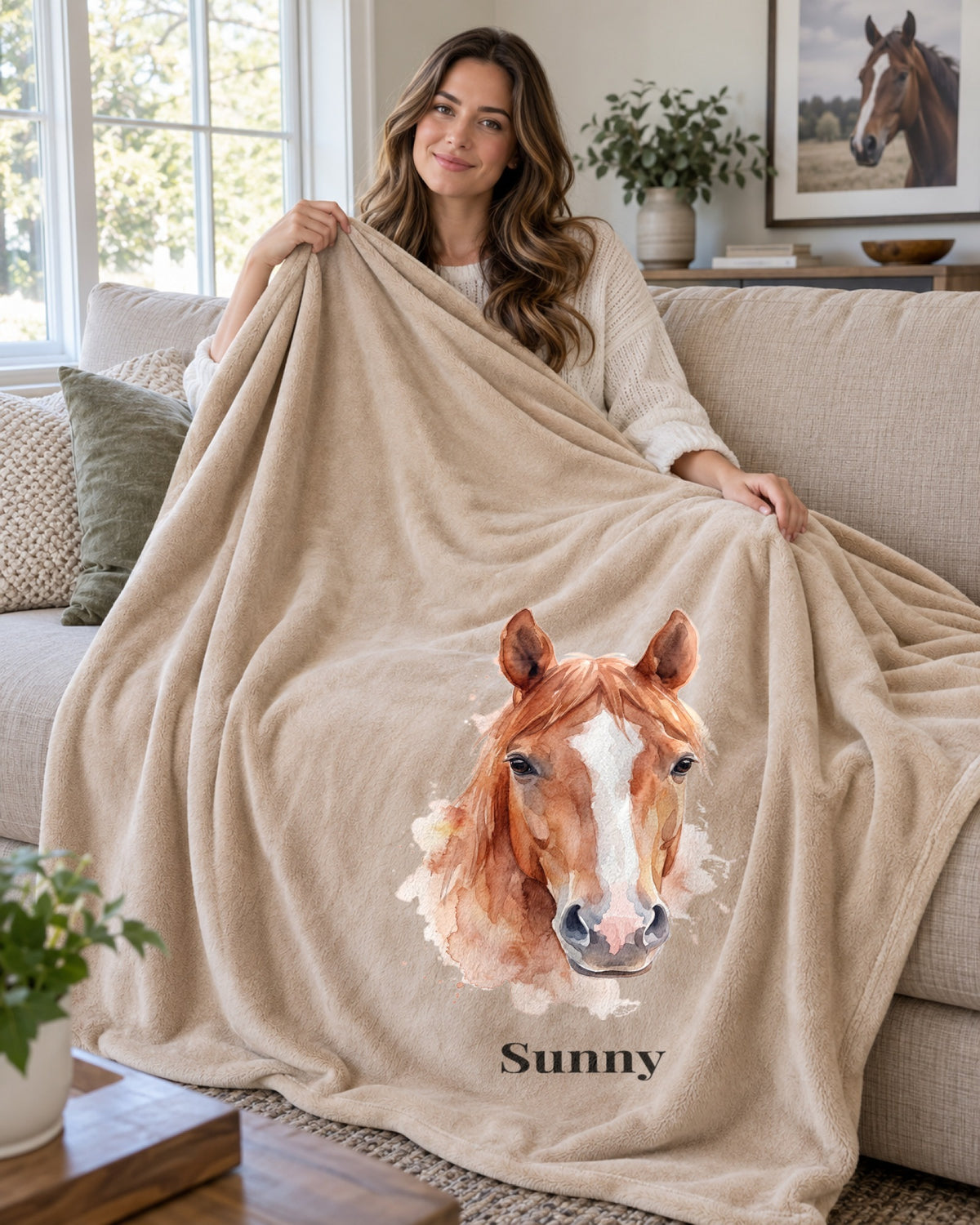 Sherpa-Decke in Beige mit Pferdeportrait im Stil Aquarell und dem Namen Sunny, von einer Frau auf dem Sofa gehalten