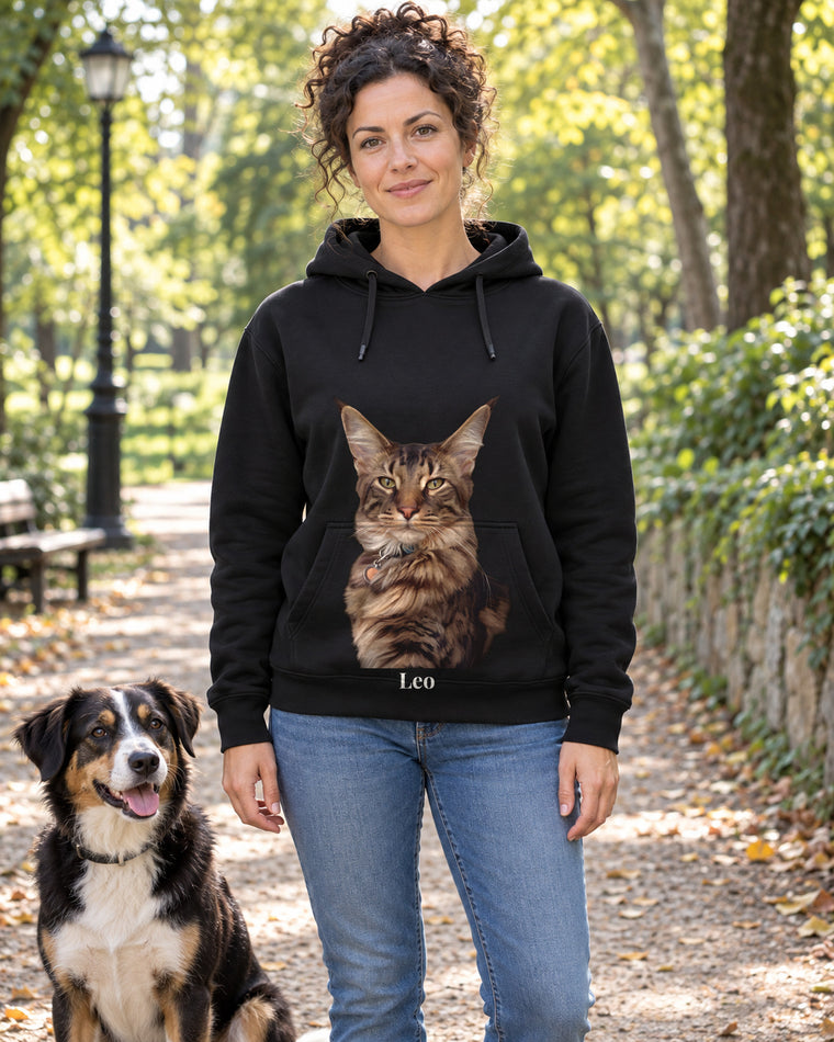 Hoodie in Flaschengrün mit Portrait von einer Maine Coon im Stil Ölgemälde und dem Namen Leo, getragen von einer Frau im Park mit ihrem Hund