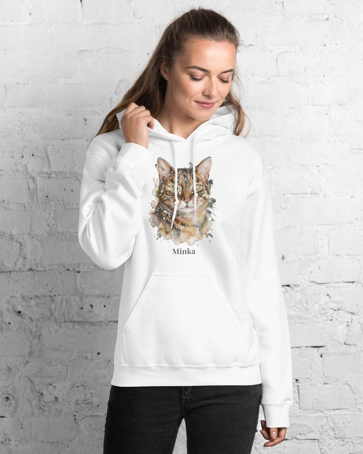 Hoodie in Weiß mit Portrait von einer Tigerkatze im Stil Aquarell und dem Namen Minka, getragen von einer Frau