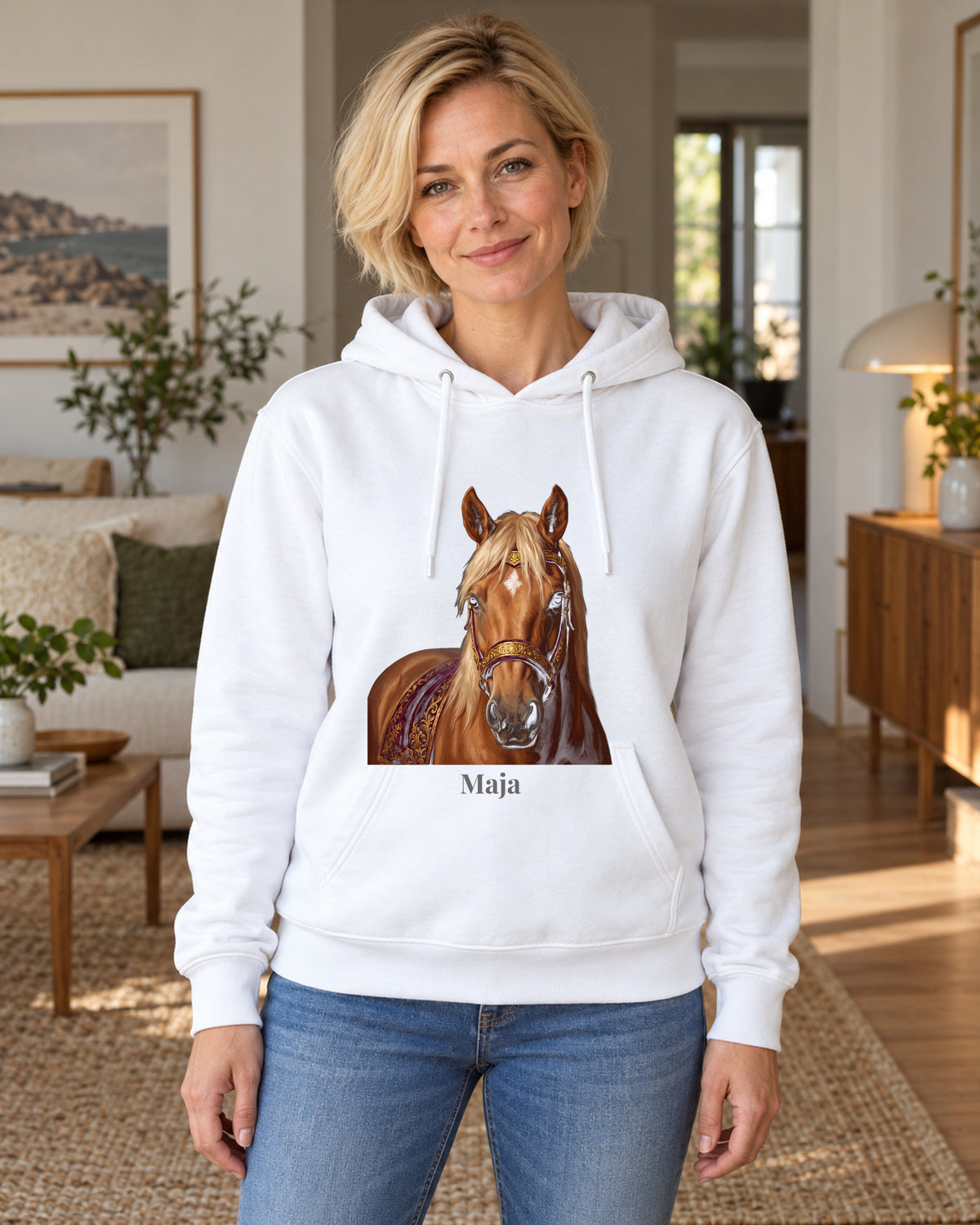 Hoodie in Hellblau mit Portrait von einem Haflinger im Stil Royal und dem Namen Maja, getragen von einer Frau in einer hellen Wohnung