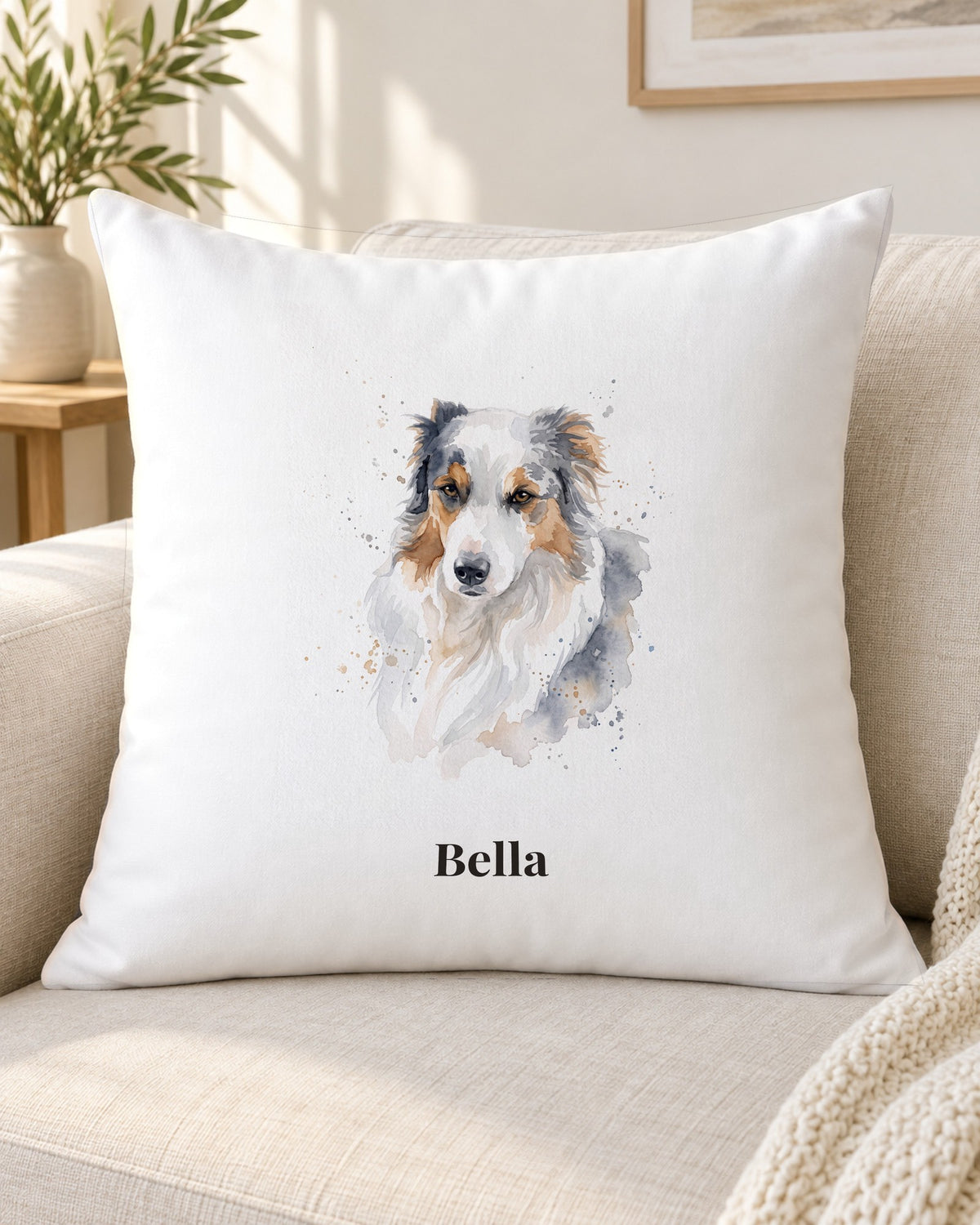 Kissen mit Hundeportrait im Aquarell-Stil und Namen Bella vor einer Wand