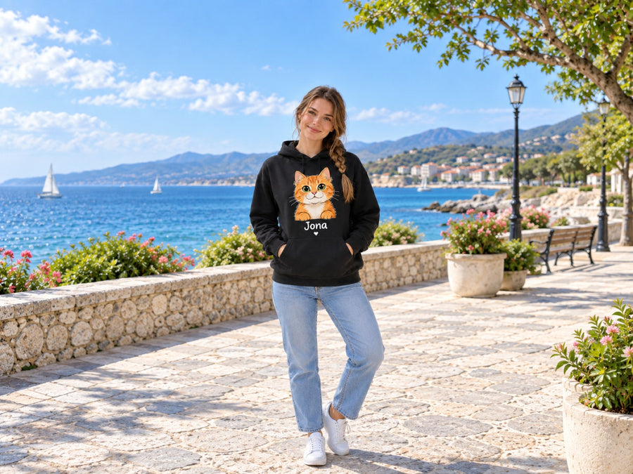 Frau im schwarzen Hoodie mit Katzenportrait im Cartoon-Stil und Namen Jona an der Promenade