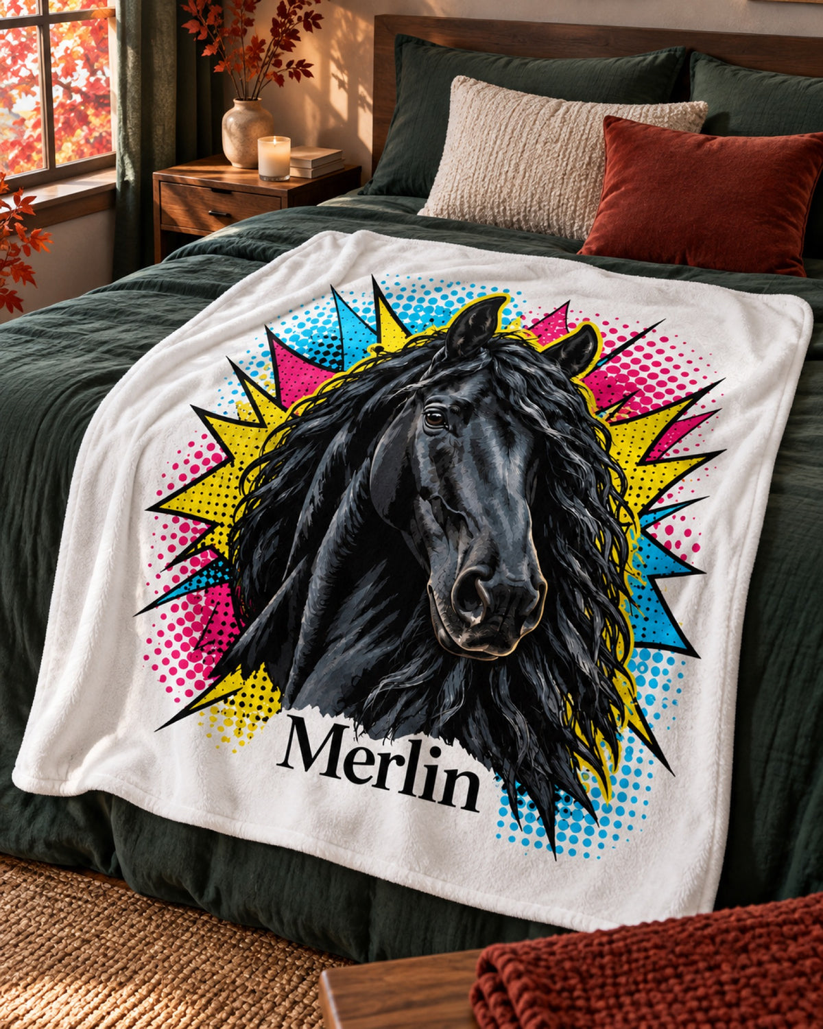 Kuscheldecke mit Rappe im Pop-Art-Stil und Namen Merlin auf einem dunkelgrünen Bett mit roten Herbstblättern am Fenster