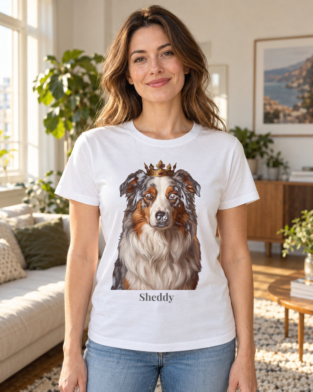 T-Shirt in Hellblau mit Portrait von einem Australian Shepherd im Stil Royal und dem Namen Sheddy, getragen von einer Frau in einer hellen Wohnung